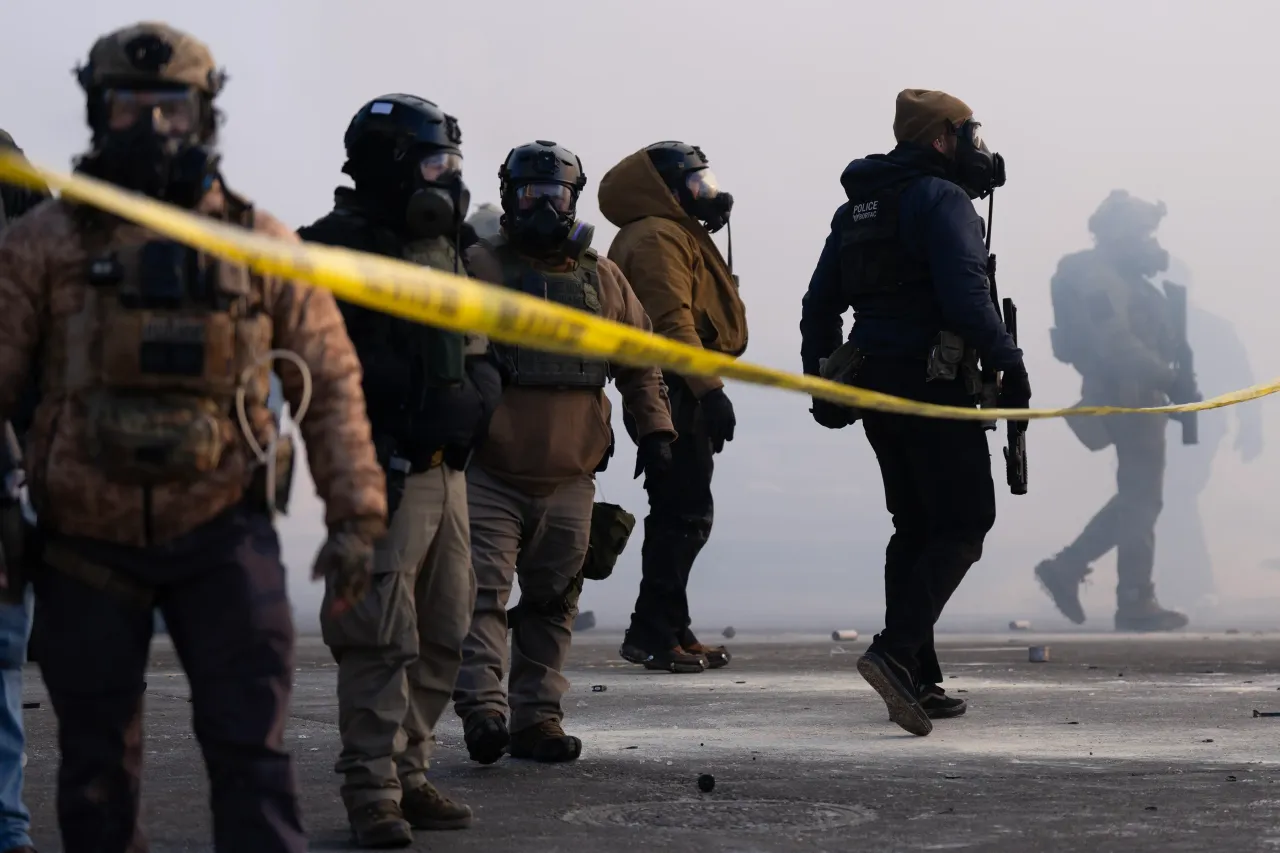 Federal agents stand in tear gas and face protesters on Nicollet Avenue near West 26th St. in south Minneapolis after Alex Pretti was fatally shot by federal agents.