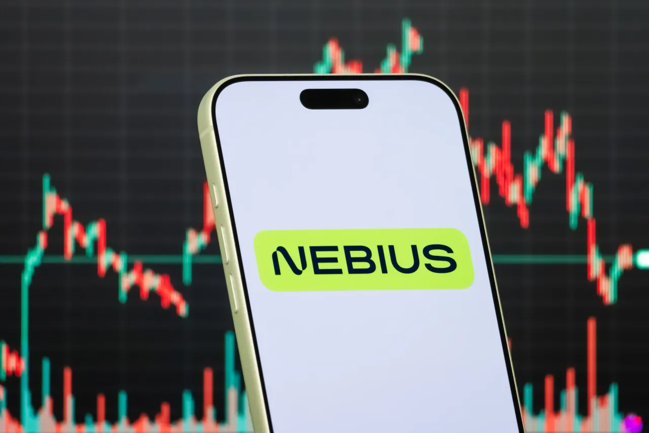 The logo of Nebius Group on a smartphone screen, with a stock chart in the background. (Photo illustration by Cheng Xin/Getty Images)