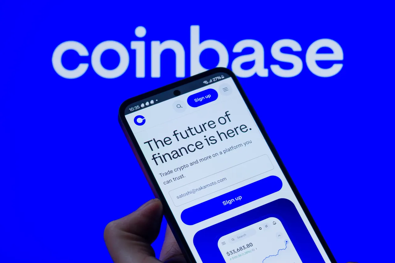 The Coinbase app is displayed on a mobile phone with the company branding icon seen in the background, in this photo illustration in Brussels, Belgium, on February 11, 2026. (Photo by Jonathan Raa/NurPhoto via Getty Images)