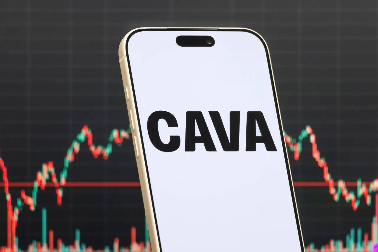 In this photo illustration, a smartphone displays the logo of CAVA Group, Inc. in front of a screen showing the company's latest stock market chart on February 15, 2026 in Qianjiang, Hubei Province, China. (Photo illustration by Cheng Xin/Getty Images)