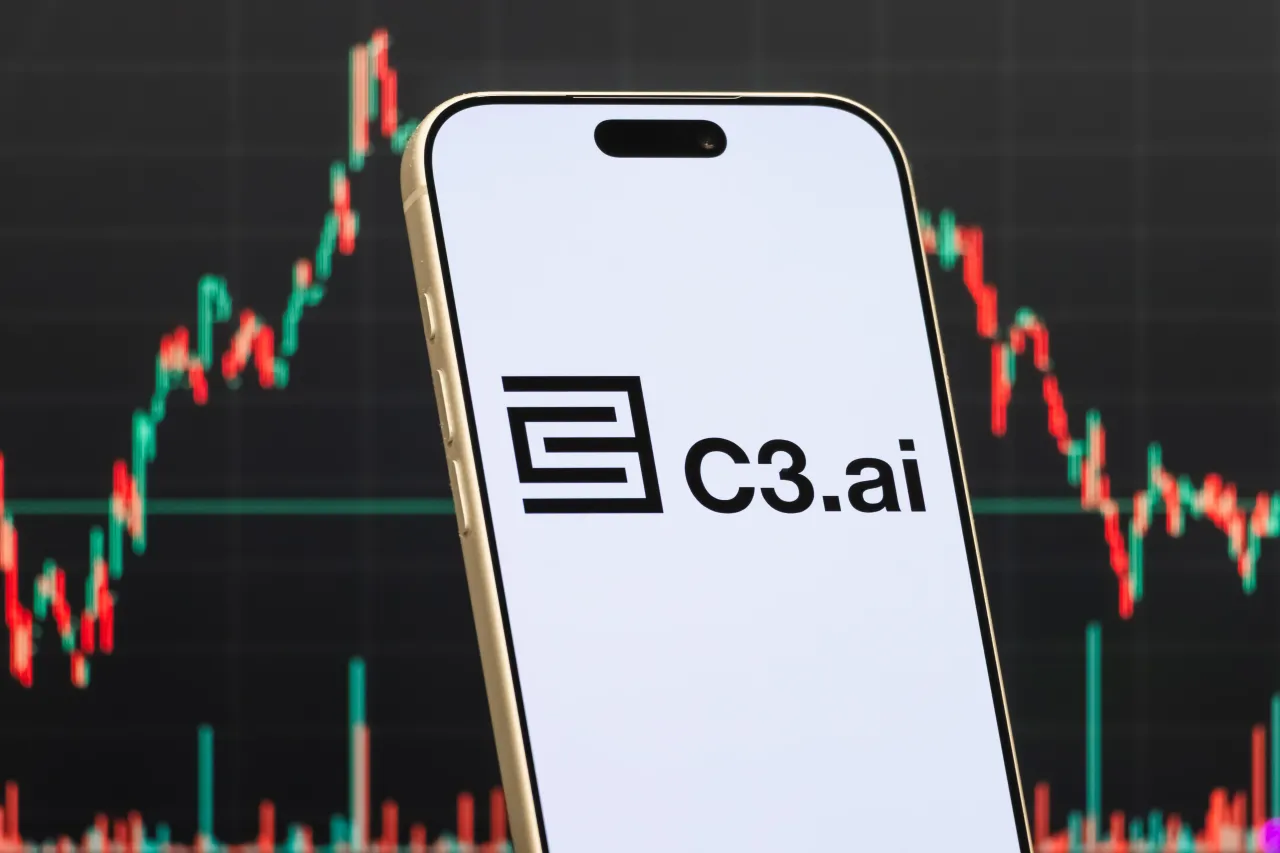 In this photo illustration, a smartphone displays the logo of C3.ai, Inc., in front of a screen showing the company's stock market chart on February 15, 2026 in Qianjiang, Hubei Province, China. (Photo illustration by Cheng Xin/Getty Images)