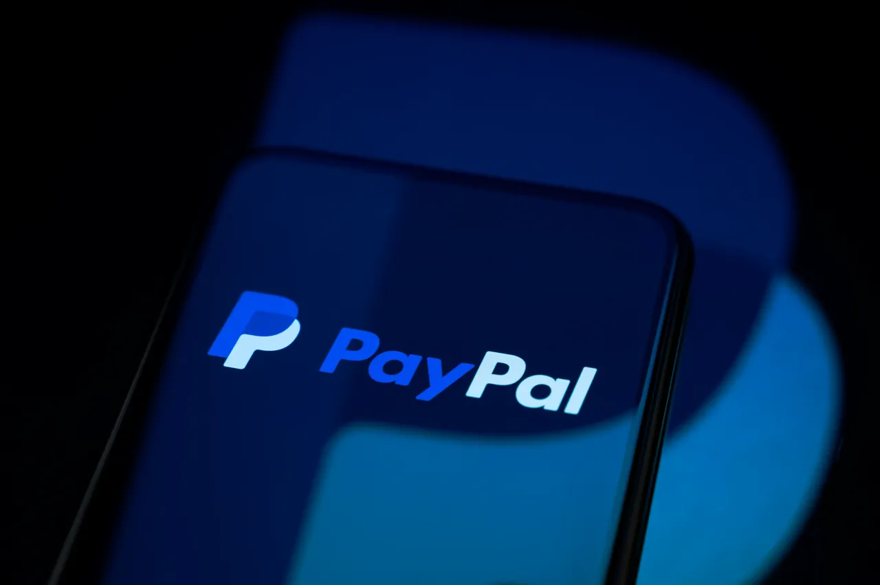 The PayPal logo appears on a smartphone screen placed on a reflective surface onto which the company's logo is projected. (Photo by Samuel Boivin/NurPhoto via Getty Images)