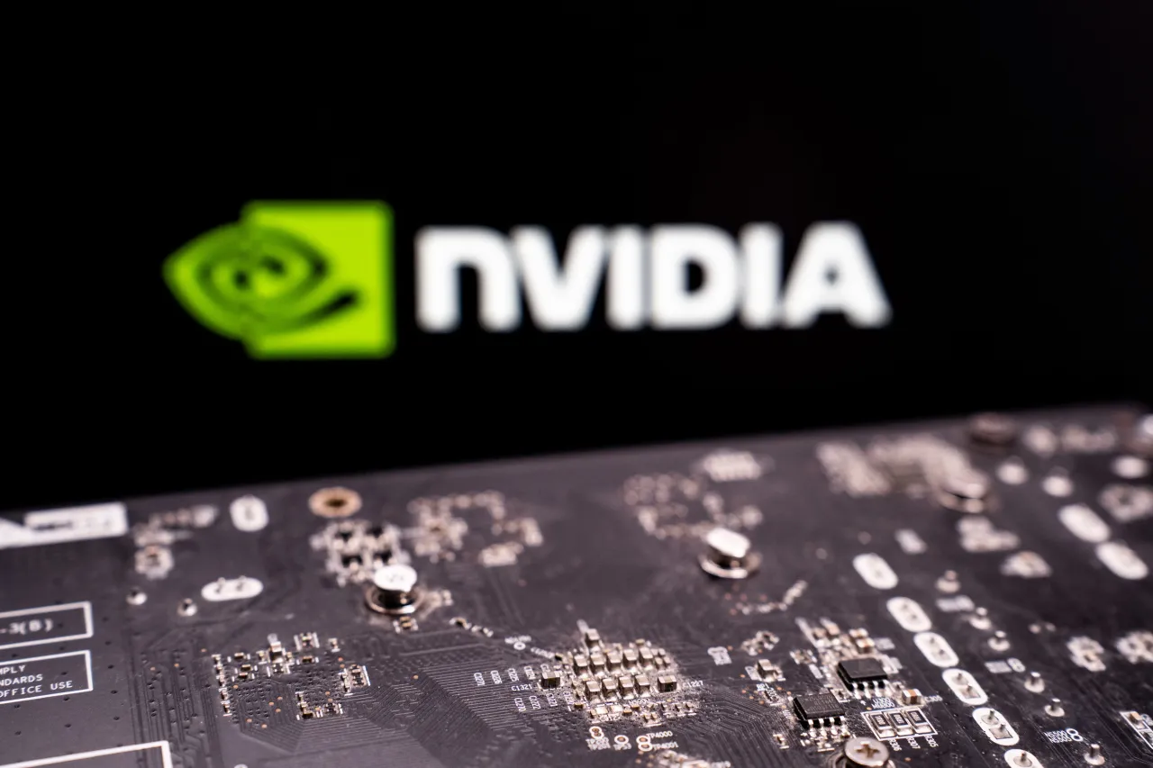 A close-up of a printed circuit board is seen with the Nvidia logo displayed on a screen in the background. (Photo by Nikos Pekiaridis/NurPhoto via Getty Images)