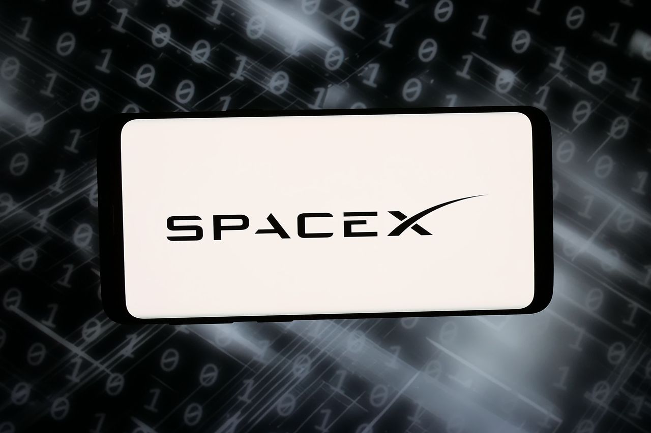 In this photo illustration, the logo of US space exploration company SpaceX is displayed on a smartphone.