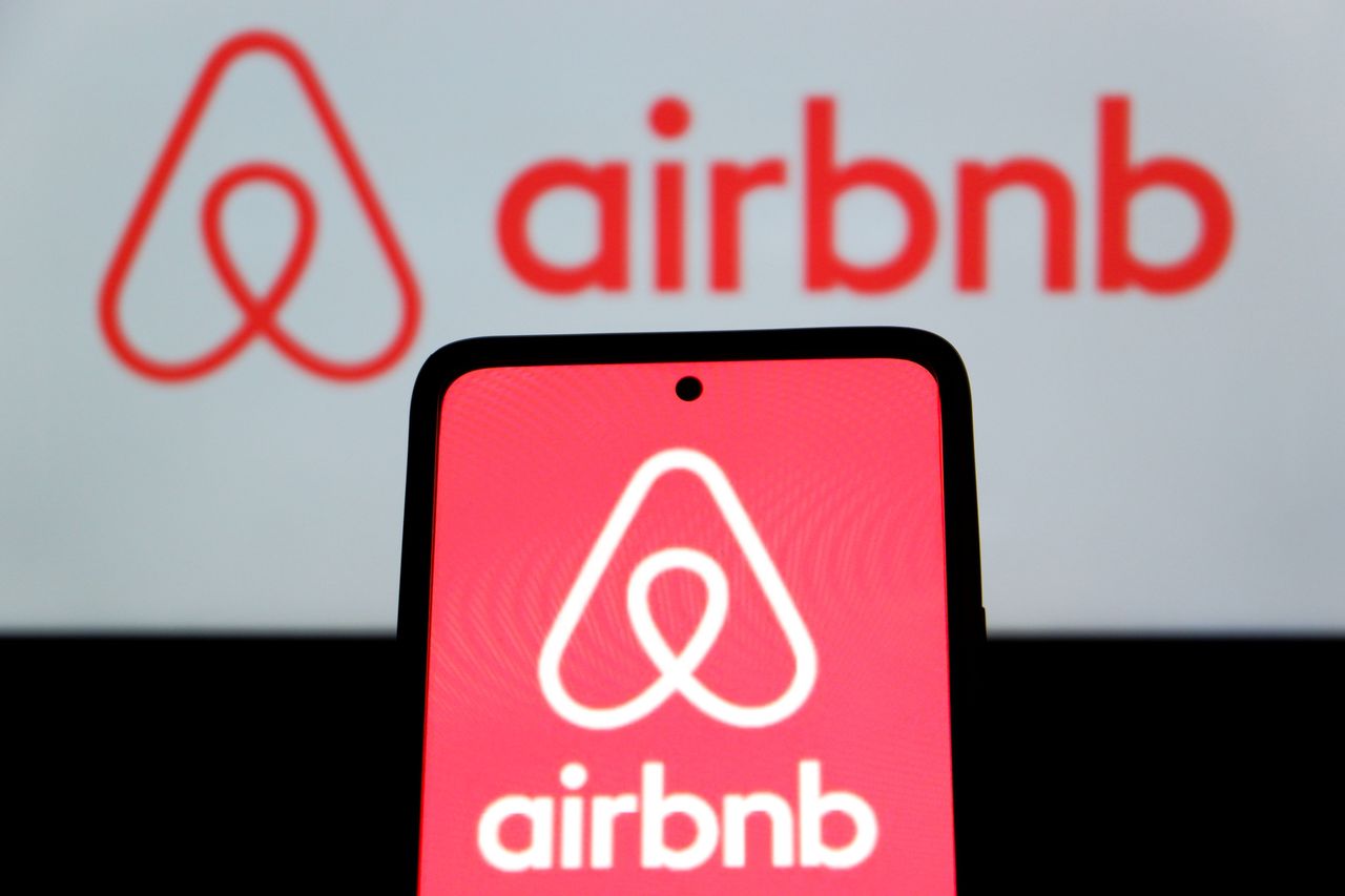 In this photo illustration, an Airbnb logo is displayed on a smartphone and in the background.