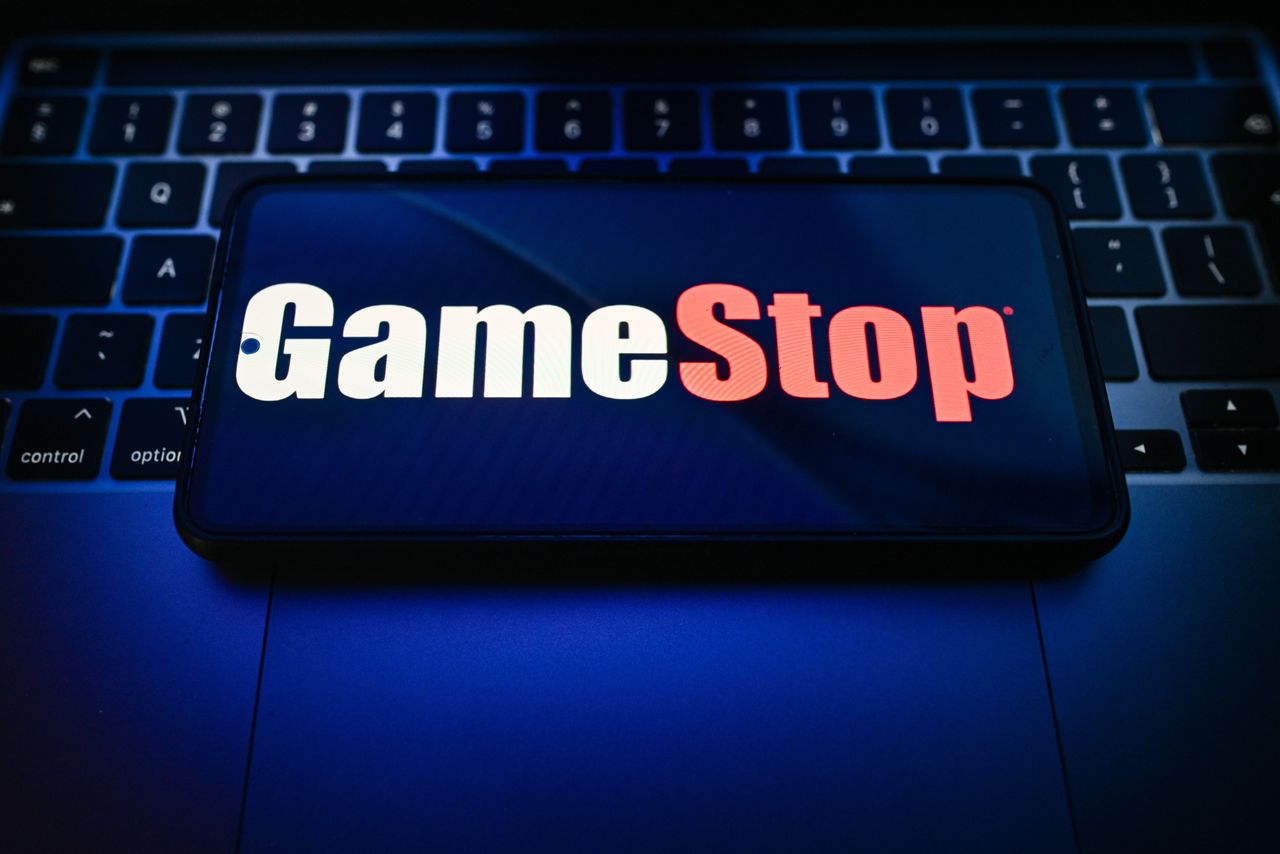 In this photo illustration, a GameStop logo is seen displayed on a smartphone on the top of a laptop.