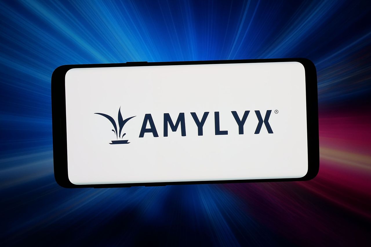 In this photo illustration, the US company Amylyx Pharmaceuticals Inc. logo is seen displayed on a smartphone in front of abstract background on computer screen. (Photo Illustration by Timon Schneider/SOPA Images/LightRocket via Getty Images)