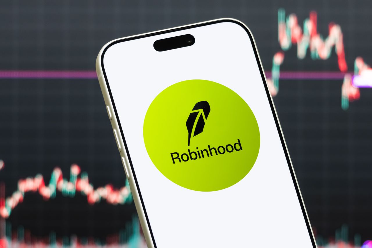 : In this photo illustration, a smartphone displays the logo of Robinhood Markets Inc. (NASDAQ: HOOD), a U.S. financial services company offering commission-free trading of stocks, options, cryptocurrencies, and other financial products, in front of a screen showing the company's latest stock market chart on July 23, 2026 in Shenzhen, Guangdong Province, China. (Photo illustration by Cheng Xin/Getty Images)