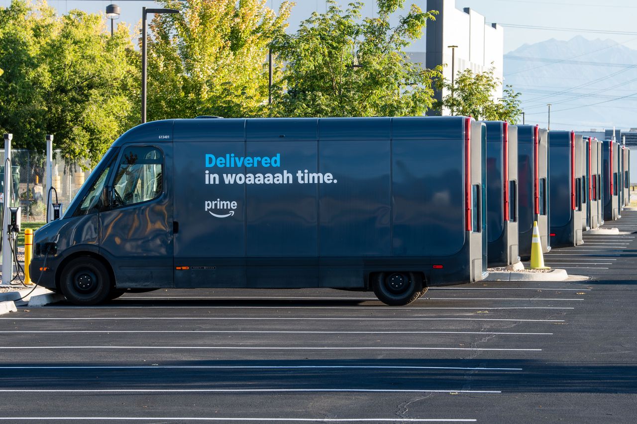 A line of Amazon Rivian electric delivery vans (EDVs) sit parked and plugged into charging stations in a fleet lot outside an Amazon fulfillment distribution facility in American Fork, Utah, United States, on September 20, 2026. (Photo by Charles-McClintock Wilson/NurPhoto via Getty Images)