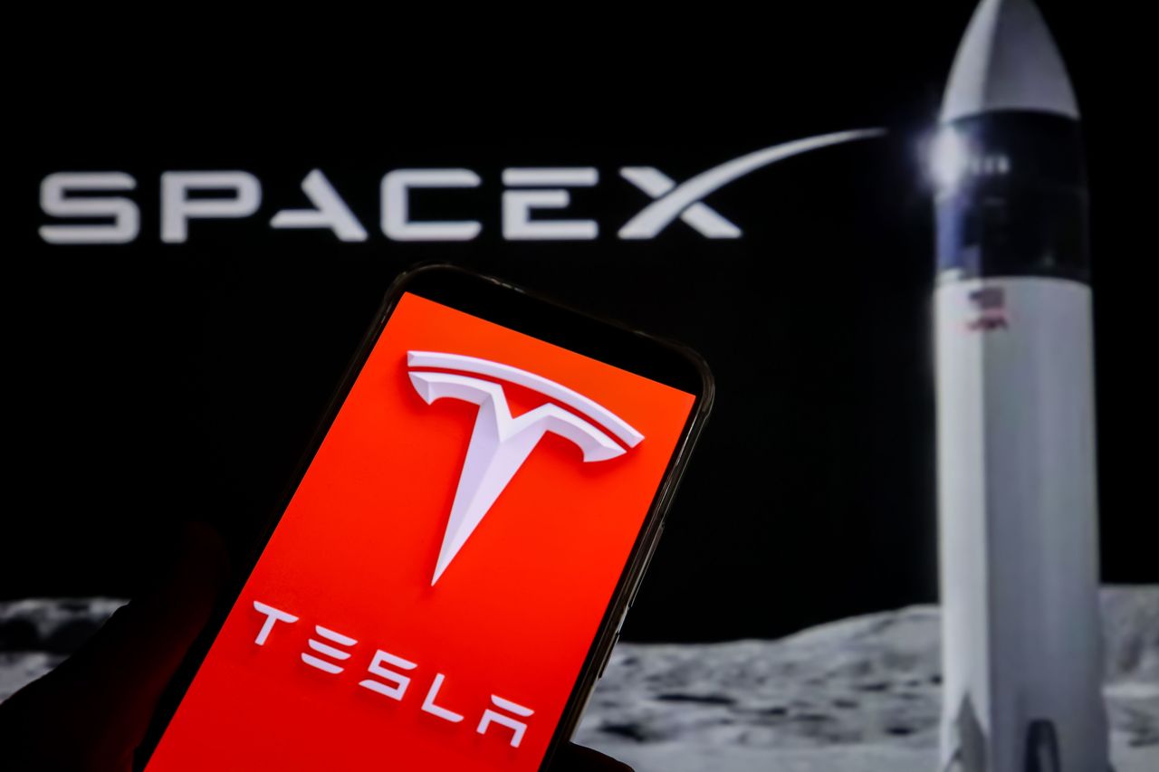 In this photo illustration, the logo of Tesla is displayed on a smartphone screen with SpaceX logo in the background on October 20, 2026 in Chongqing, China. (Photo by VCG/VCG via Getty Images)