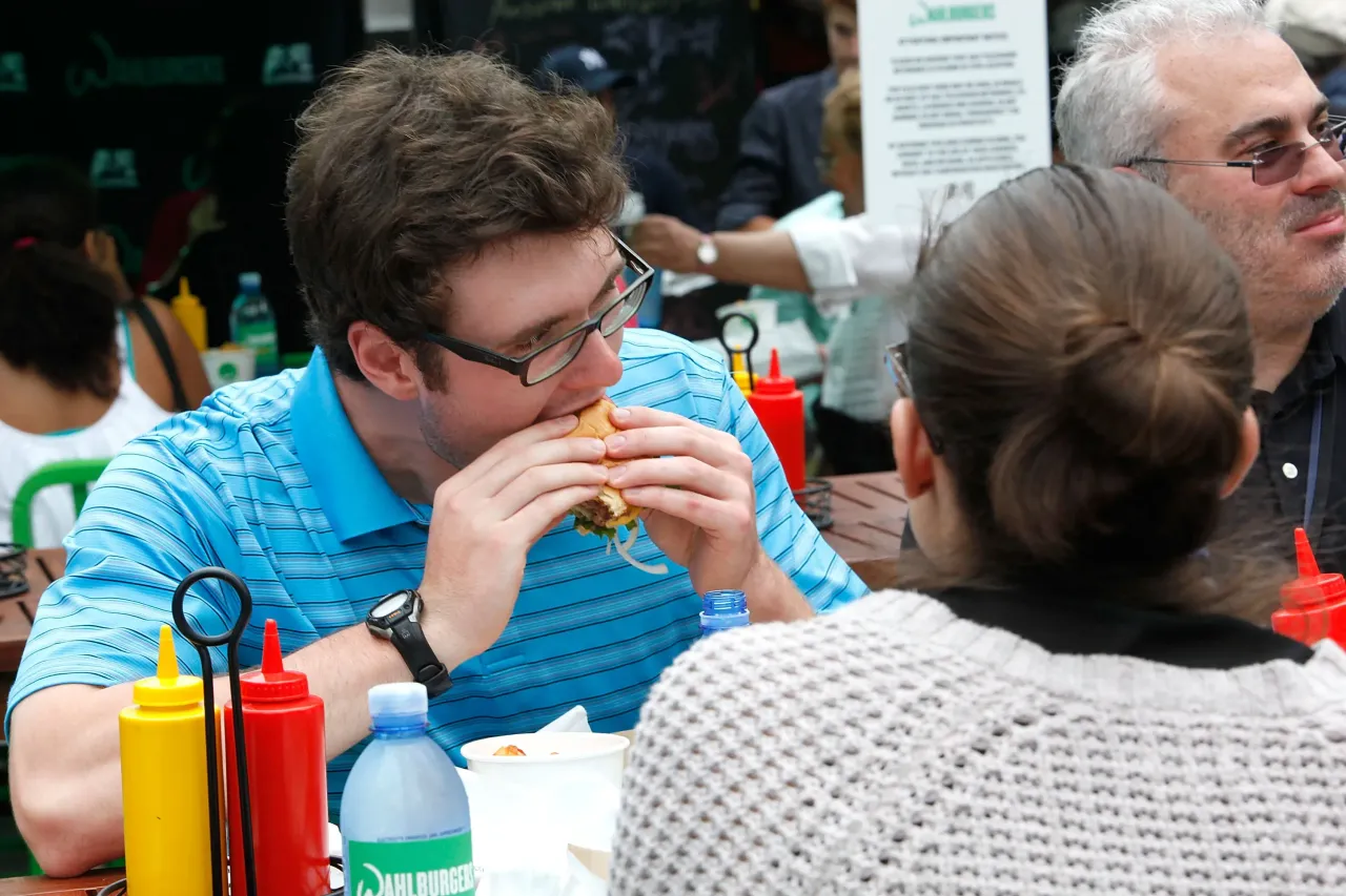 A person eating a burger at an outdoor cafe in New York City. (Photo by Thos Robinson/Getty Images for A+E Networks)