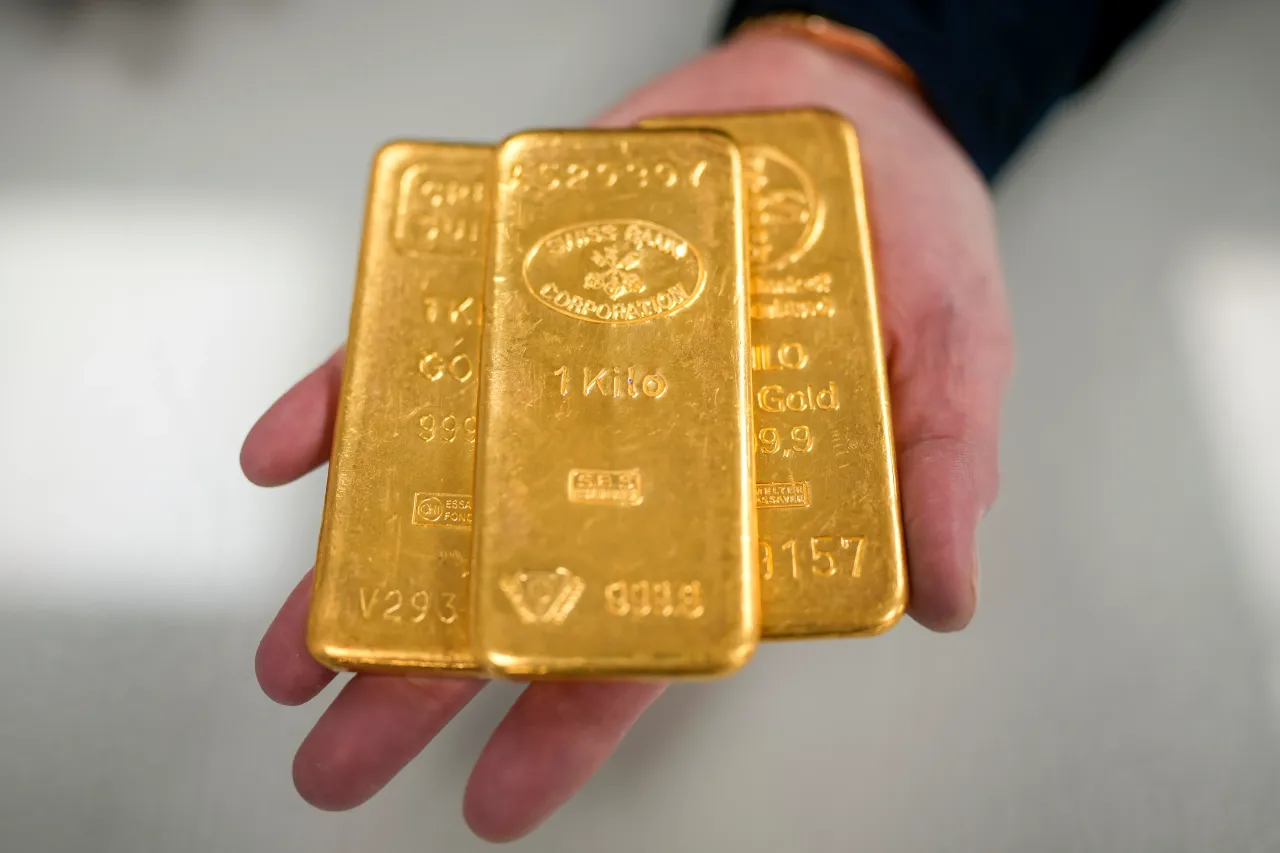 A jewelry quarter gold dealer poses with three 1kg gold bullion bars on December 13, 2023 in Birmingham, England.