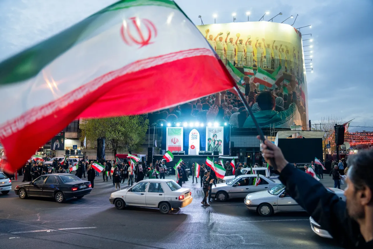 People wave flags as they demonstrate in support of the Iranian government on March 22, 2026 in central Tehran, Iran