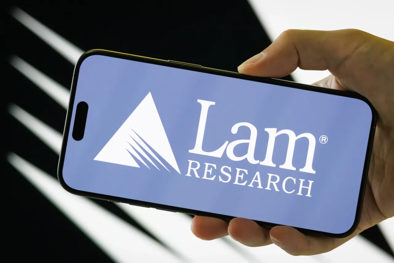 In this photo illustration, a person holds a smartphone displaying the logo of Lam Research Corporation (NASDAQ: LRCX) on July 28, 2025, in Chongqing, China. 
