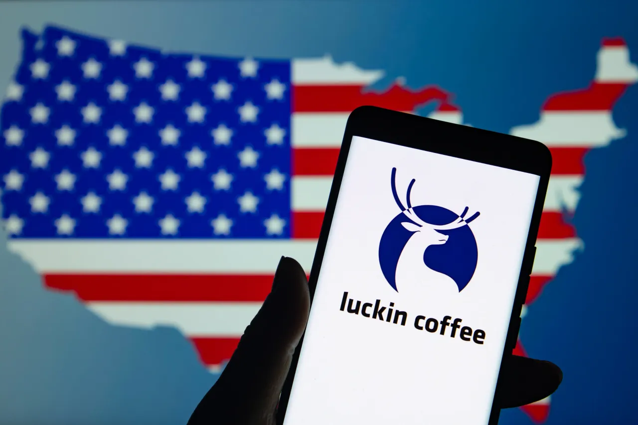 An illustration photo shows the Luckin Coffee LOGO displayed on a smartphone with the American flag in the background in Chongqing, China on July 1, 2025. (Photo credit CFOTO/Future Publishing via Getty Images)