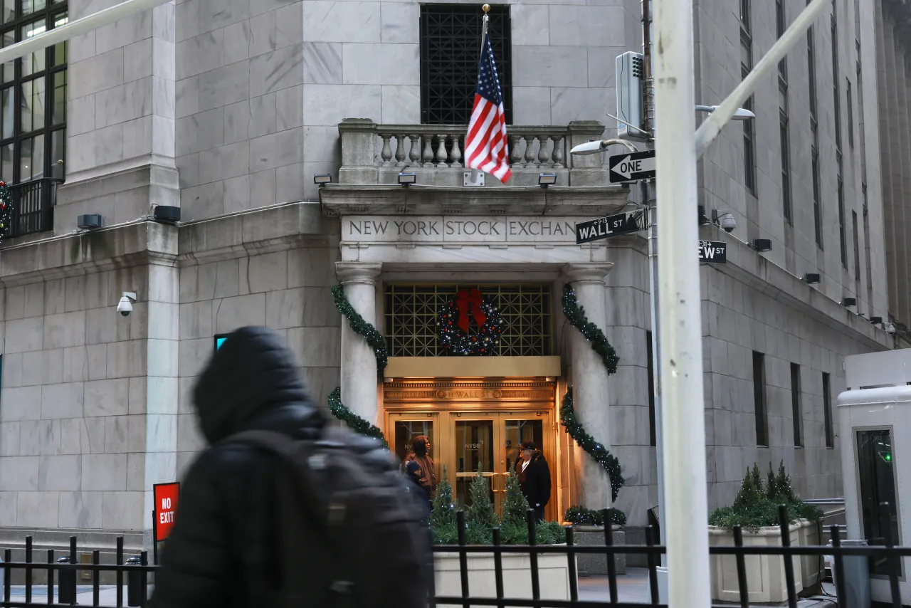 People walk by the New York Stock Exchange (NYSE) on December 30, 2025 in New York City. The Dow opened largely unchanged in morning trading following its steepest one-day decline in nearly two weeks. 