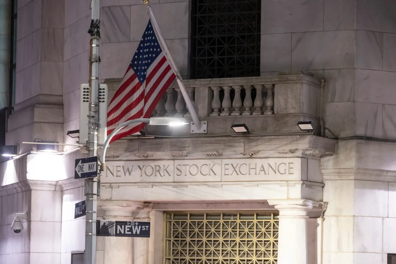 Night view of the illuminated exterior of New York Stock Exchange with a big American flag from the front facade, pictured in November 2024 in NYC, USA.