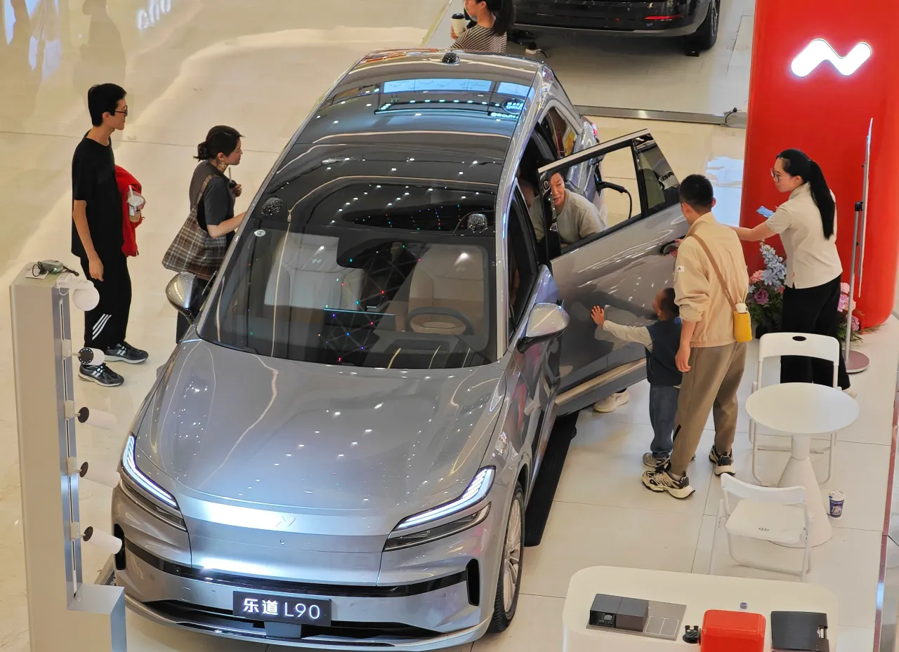 Customers learn about the ONVO L90 electric vehicle at a shopping mall in Qingdao, Shandong, China on October 15, 2025. 