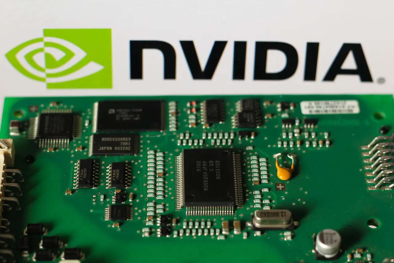 In this photo illustration, the Nvidia logo is seen in the background beside a printed circuit board (PCB). 