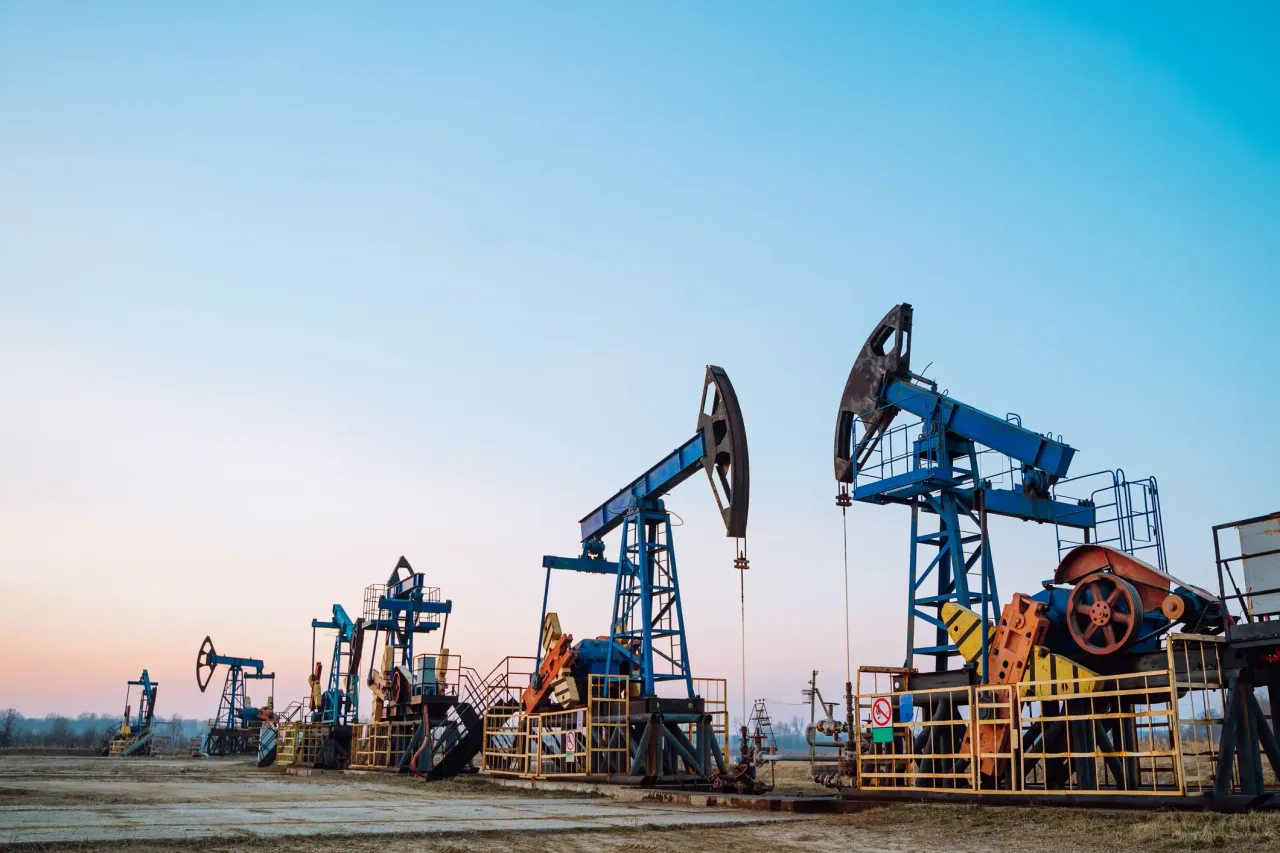 Row of oil pumps in blue color on a clear sky background, sunset. Siberia. 