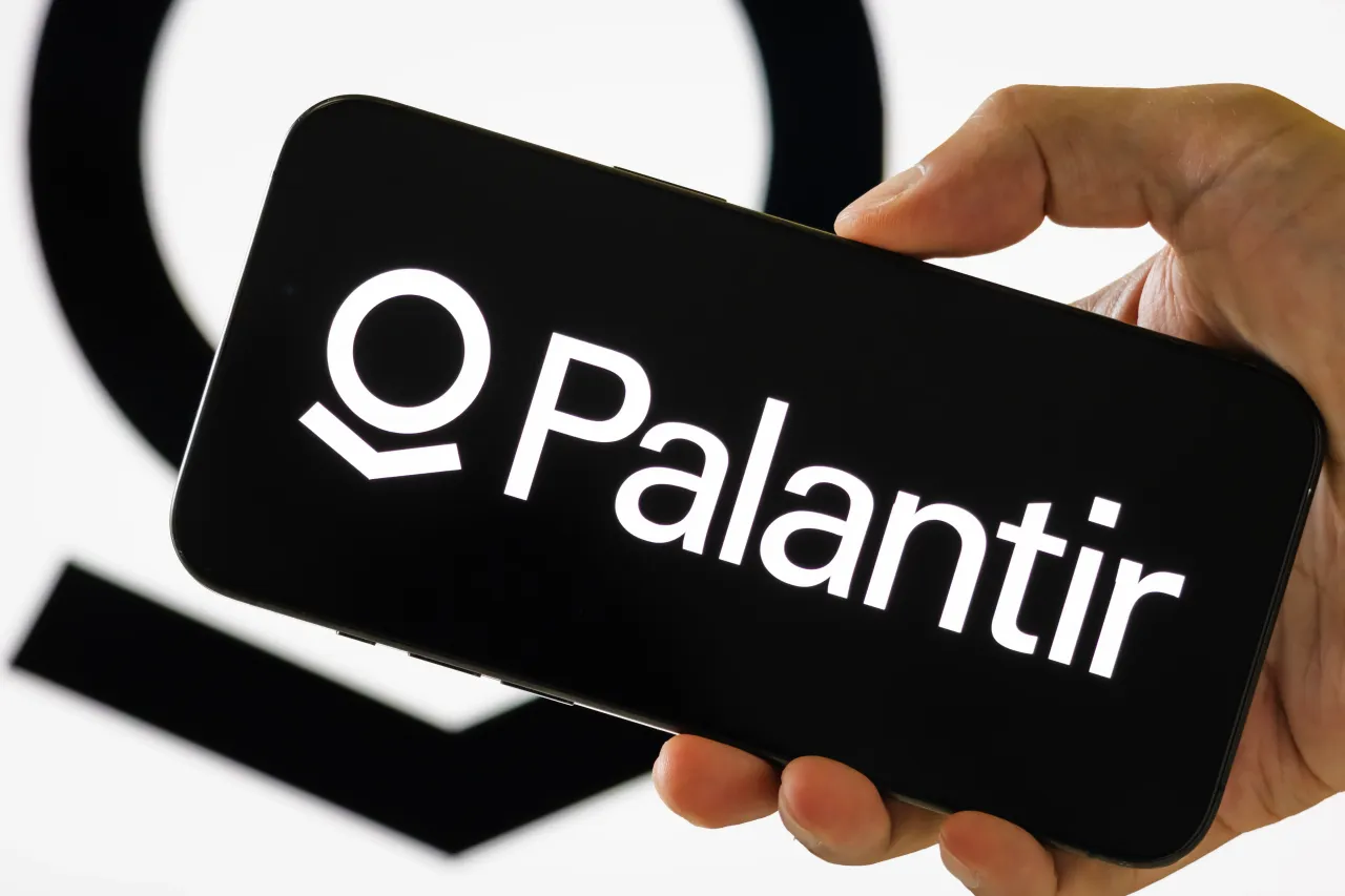 In this photo illustration, a person holds a smartphone displaying the logo of Palantir Technologies, with the company's circular emblem visible in the background, on July 30, 2025, in Chongqing, China. 