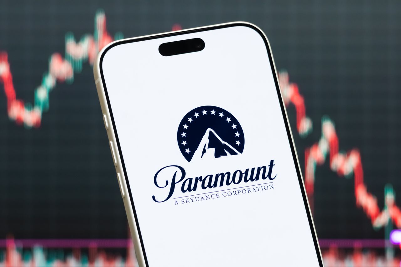 A smartphone displays the logo of Paramount Skydance Corp in front of a screen showing the company's stock market chart on July 27, 2026. (Photo illustration by Cheng Xin/Getty Images)