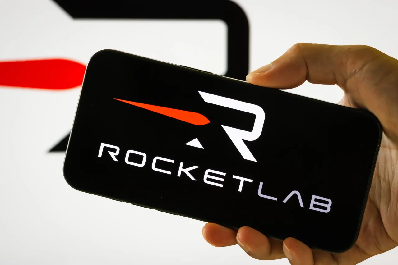  In this photo illustration, a person holds a smartphone displaying the logo of Rocket Lab USA Inc.