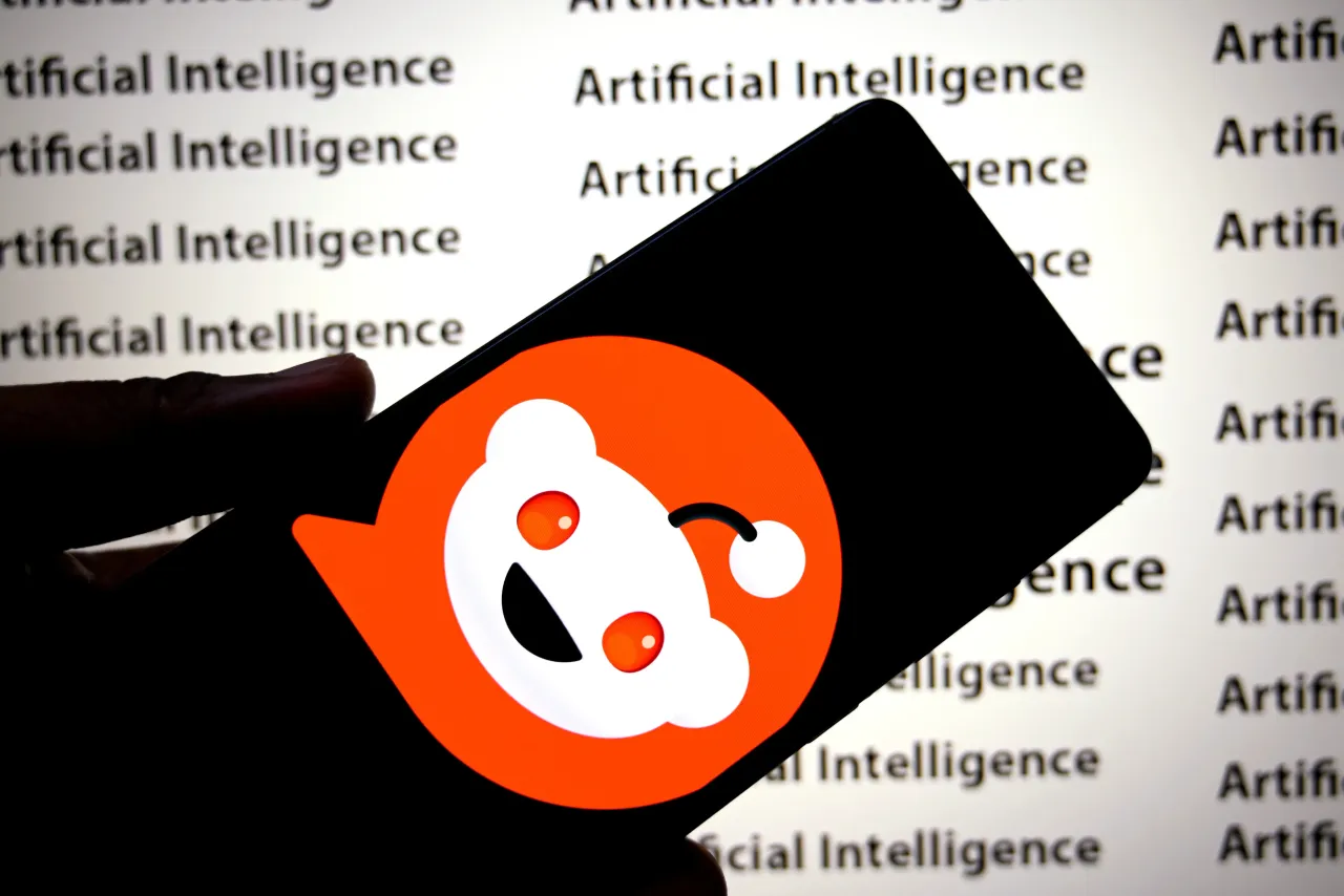 In this photo illustration, a Reddit logo is seen displayed on a smartphone with an Artificial Intelligence (inscriptions) in the background. 