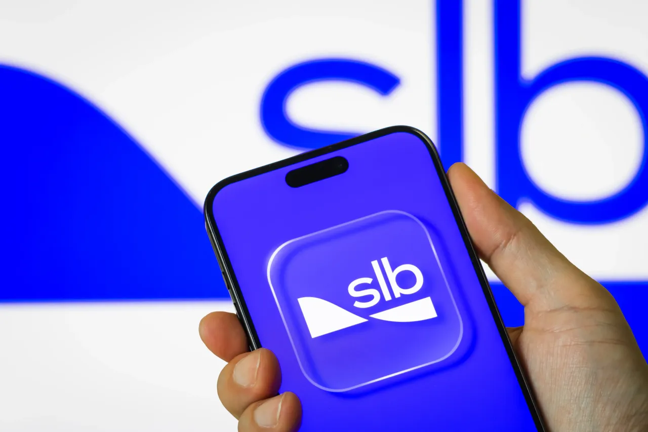In this photo illustration, a person holds a smartphone displaying the logo of Schlumberger Limited (NYSE: SLB), an American oilfield services company.