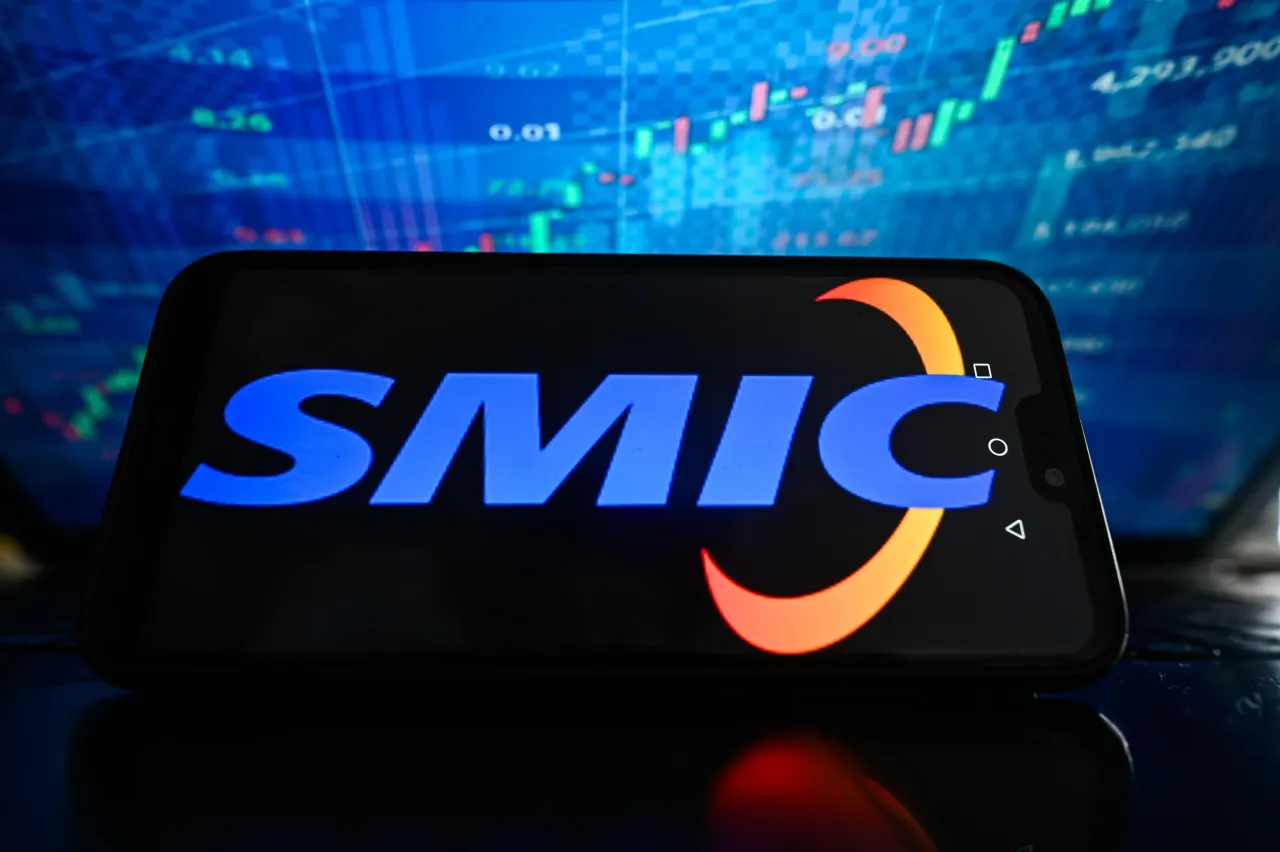 n this photo illustration, a SMIC logo is displayed on a smartphone with stock market percentages in the background.