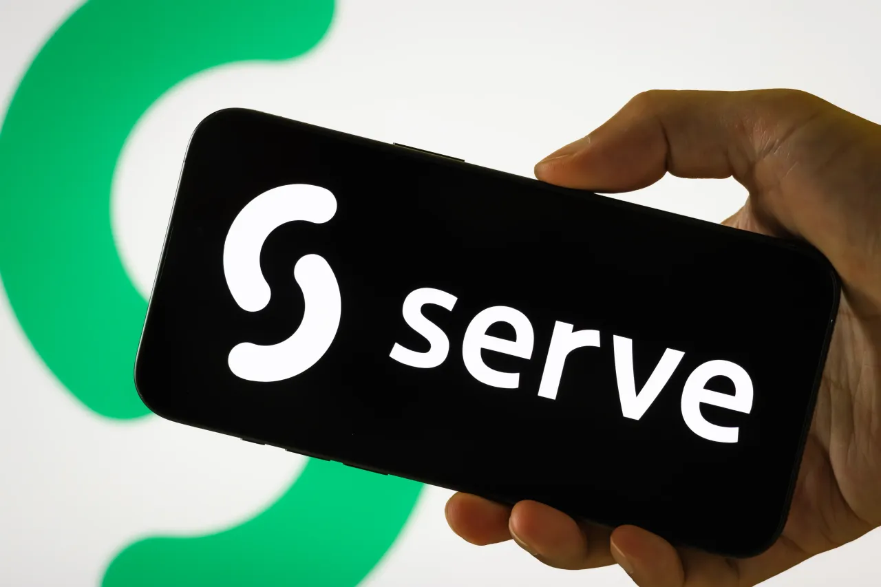 In this photo illustration, a person holds a smartphone displaying the logo of Serve Robotics. 