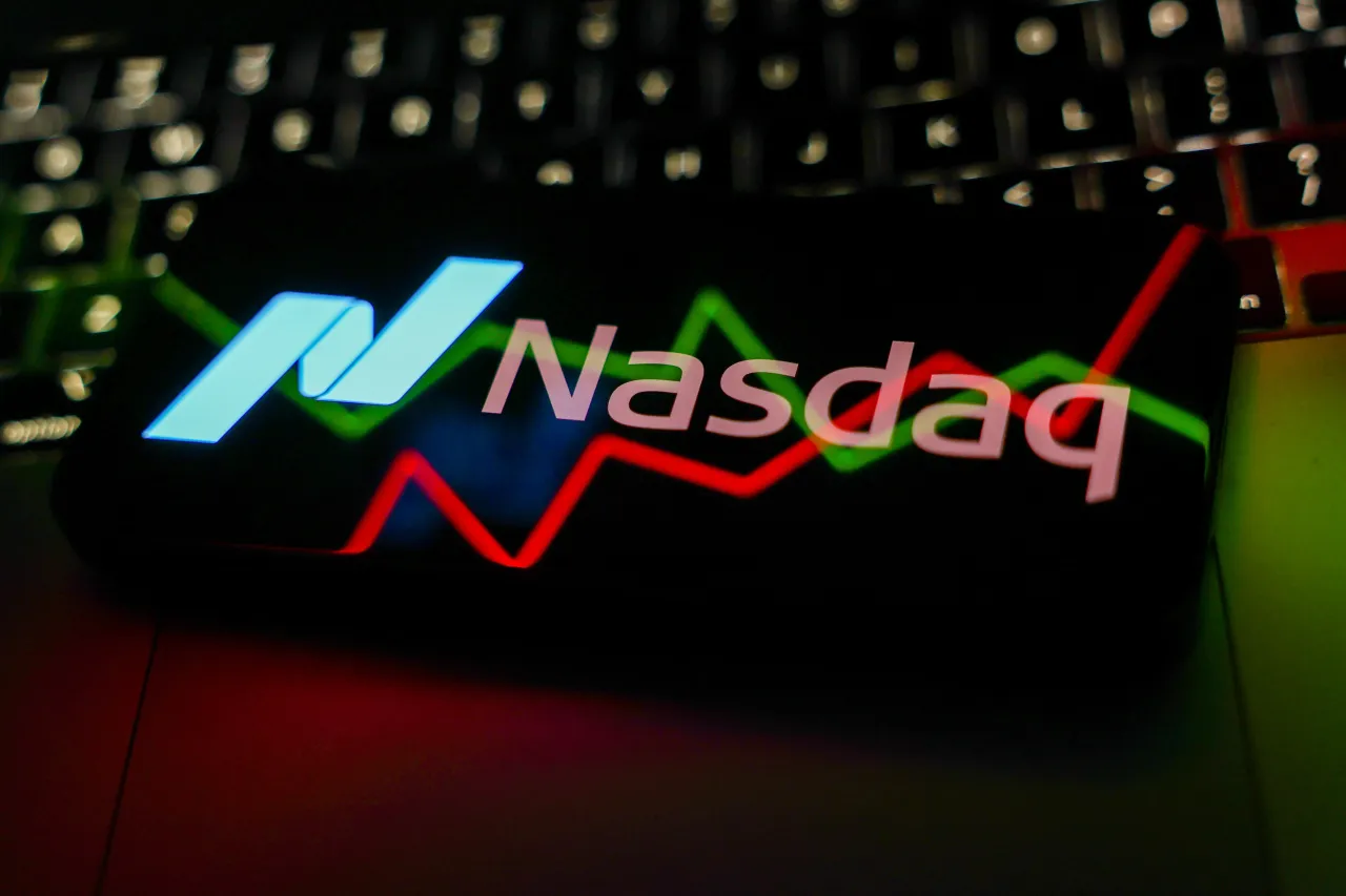 A laptop keyboard, a reflected illustrative stock graph displayed on a screen.