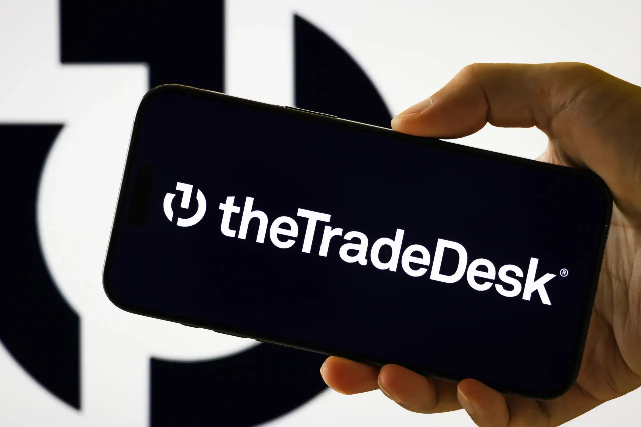 In this photo illustration, a person holds a smartphone displaying the logo of Trade Desk Inc. (NASDAQ: TTD), on Aug. 7, 2025, in Chongqing, China. 