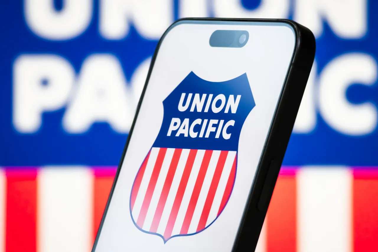 In this photo illustration, the Union Pacific logo is displayed on a smartphone screen, with the company's iconic red, white, and blue shield emblem visible in the background, on April 20, 2025.
