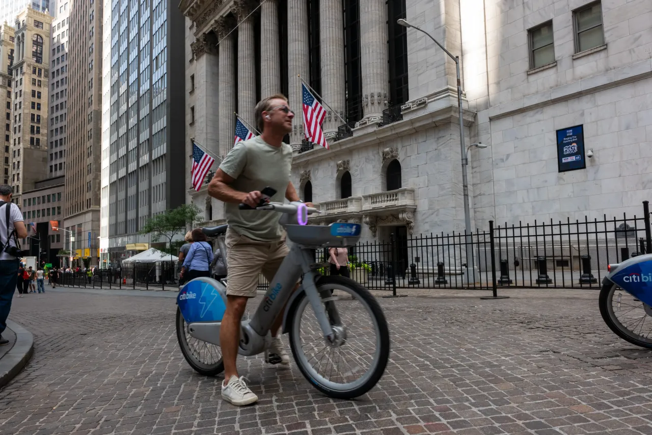 A man rides a Citi Bike outside the New York Stock Exchange (NYSE) in lower Manhattan on September 03, 2025, in New York City. The Dow was down over 150 points in morning trading. 