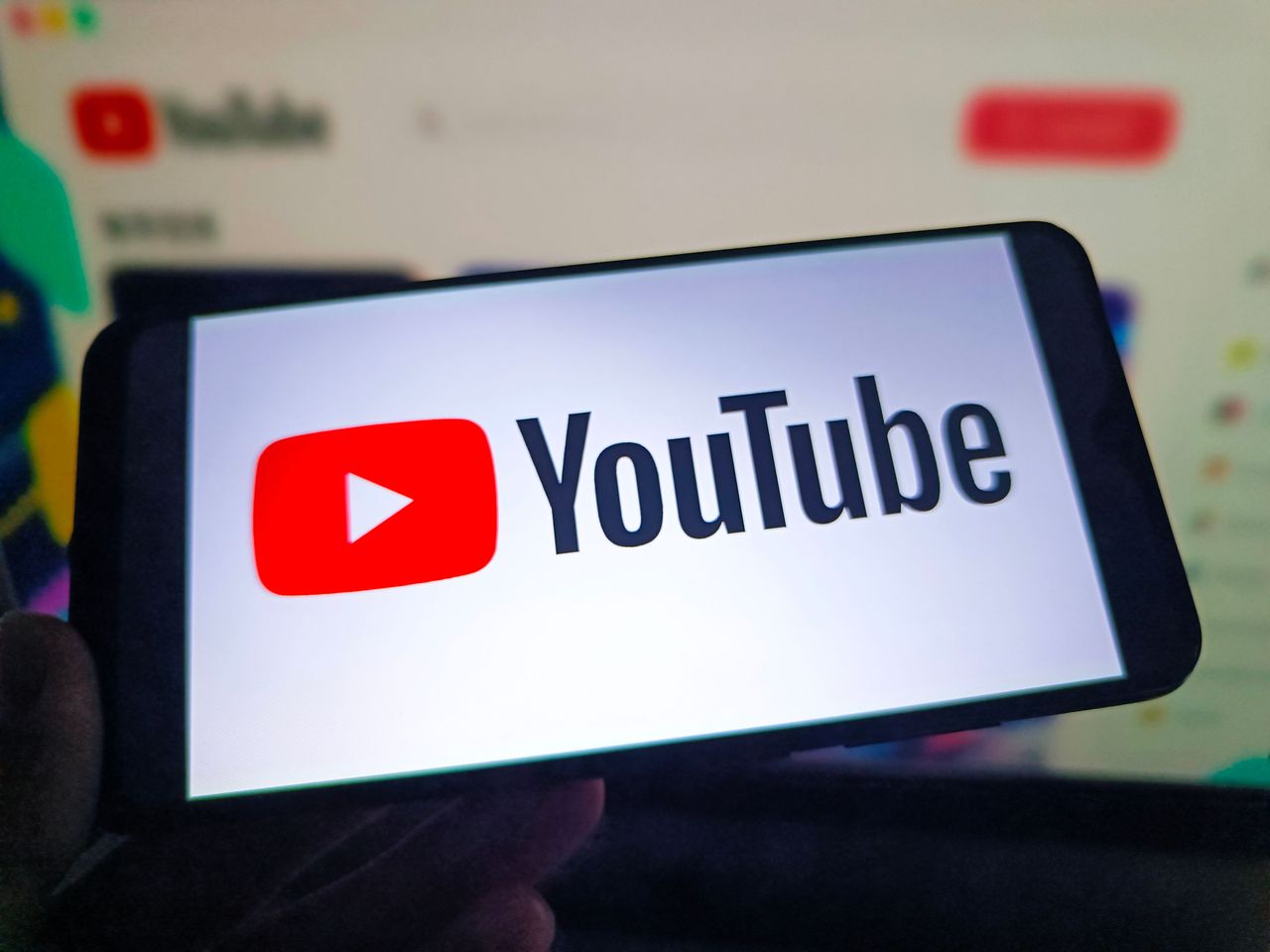 A netizen is using his mobile phone to view YouTube logo and using his computer to view YouTube webpage. (Photo credit should read CFOTO/Future Publishing via Getty Images)