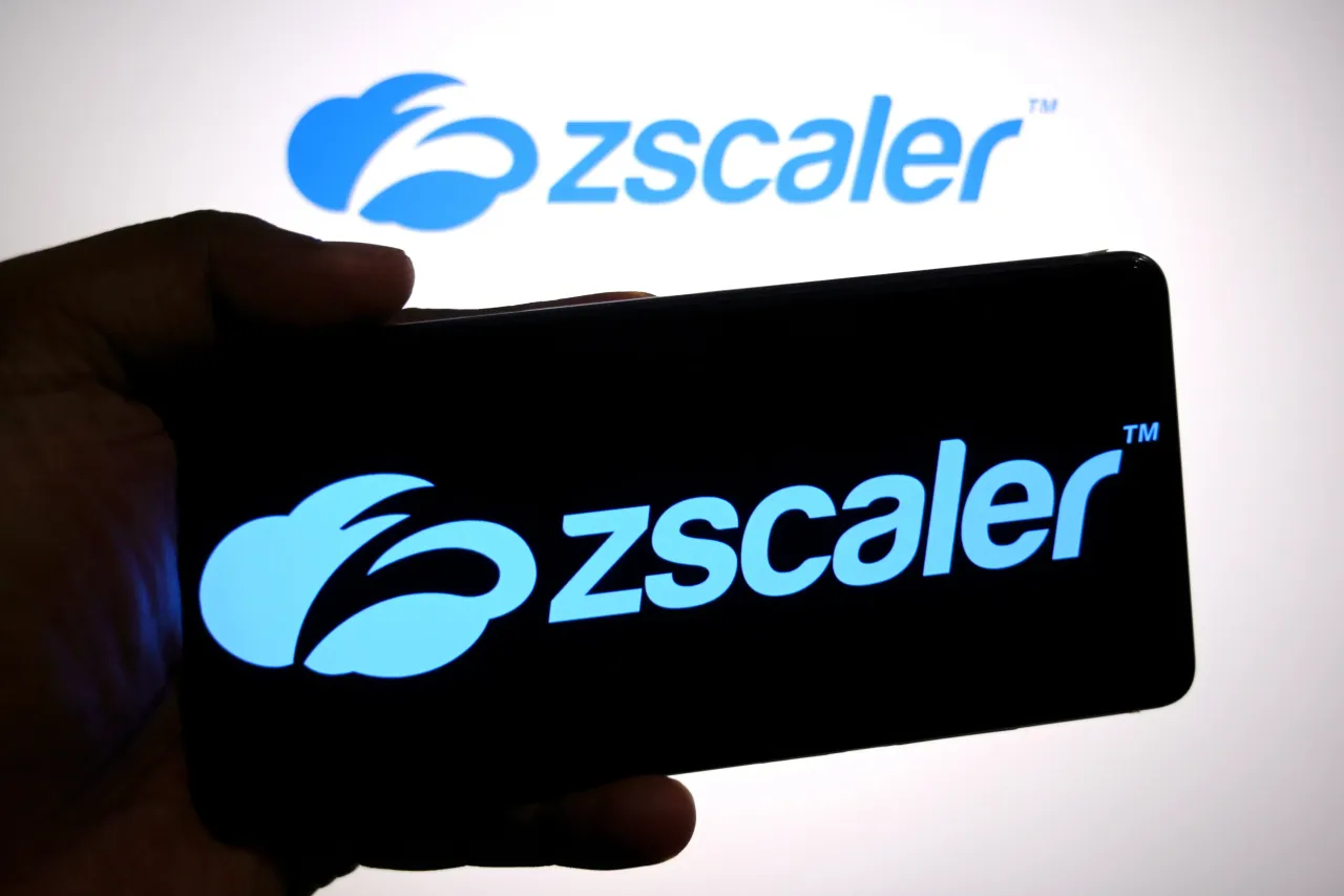 In this photo illustration, a Zscaler logo is seen displayed on a smartphone and in the background. 