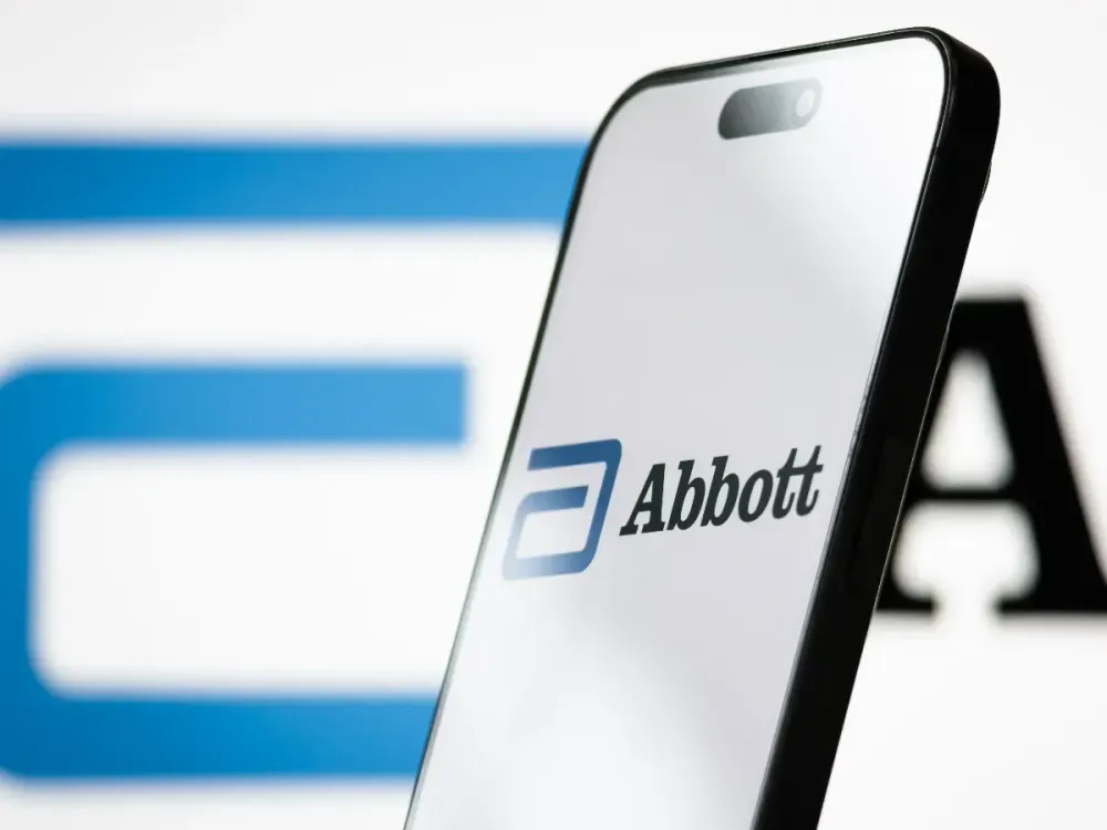 In this photo illustration, the Abbott logo is displayed on a smartphone screen, with the company's branding blurred in the background, on April 14, 2025 in Chongqing, China. (Photo by Cheng Xin/Getty Images)