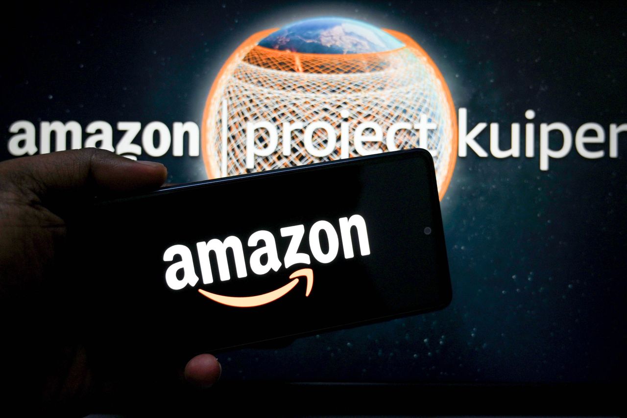  In this photo illustration, an Amazon logo is seen displayed on a smartphone with an Amazon project Kuiper logo in the background. (Photo Illustration by Avishek Das/SOPA Images/LightRocket via Getty Images)
