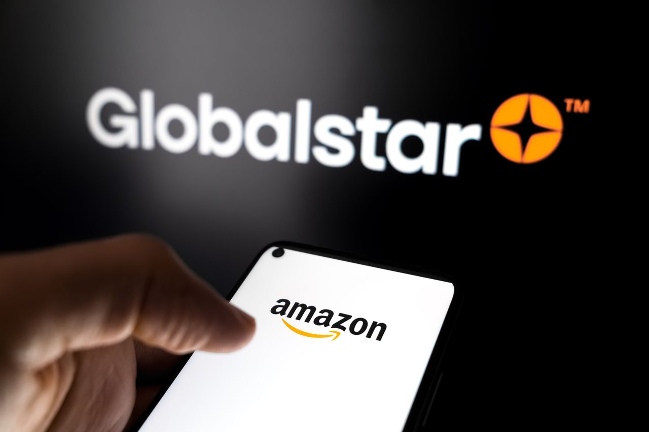 The Amazon logo appears on a smartphone screen, and the Globalstar logo displays as the background on a laptop computer screen in this photo illustration in Athens, Greece, on April 15, 2026. (Photo by Nikolas Kokovlis/NurPhoto via Getty Images)