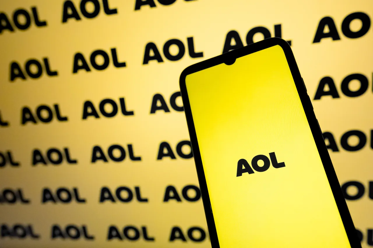 The AOL logo appears on a smartphone screen, and as the background on a laptop screen in this photo illustration in Athens, Greece, on August 11, 2025. (Photo by Nikolas Kokovlis/NurPhoto via Getty Images)