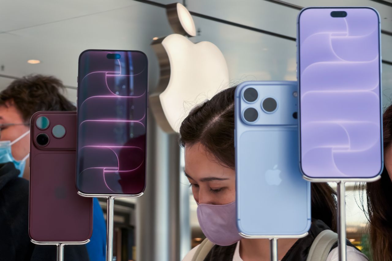 Customers stand behind a display of newly released iPhone 18 Pro and iPhone 18 Pro Max models, with an illuminated Apple logo in the background, at an Apple Store on September 18, 2026, in Hong Kong, China. (Photo by Cheng Xin/Getty Images)