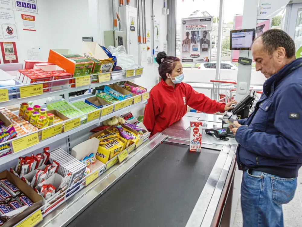 A customer buying milk in the check out line with the cashier at a Tiendas store in Colombia (Photo by: Jeffrey Greenberg/Universal Images Group via Getty Images)