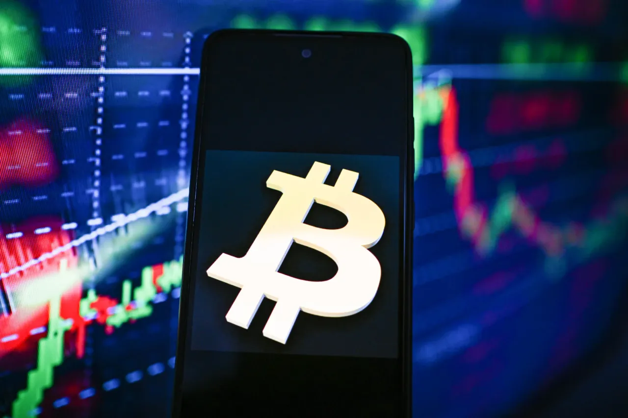 In this photo illustration, a Bitcoin logo is seen displayed on a smartphone with stock market percentages on the background. (Photo Illustration by Omar Marques/SOPA Images/LightRocket via Getty Images)