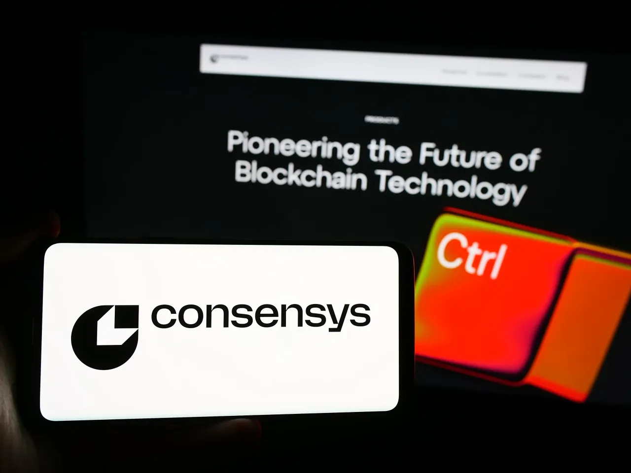In this photo illustration, US blockchain software company Consensys Inc. logo seen displayed on a smartphone in front of website. (Photo Illustration by Timon Schneider/SOPA Images/LightRocket via Getty Images)