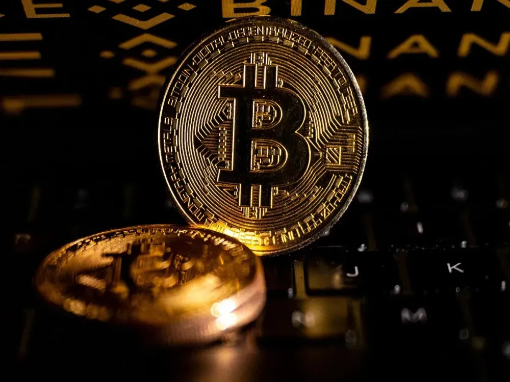 In this photo illustration Bitcoin cryptocurrency coins are seen in front of a screen displaying 'Binance' logo in Ankara, Turkiye on March 24, 2025. (Photo by Didem Mente/Anadolu via Getty Images)