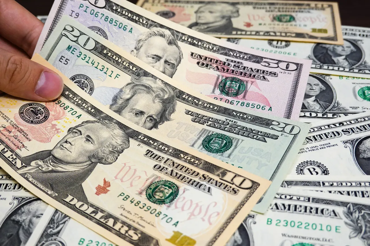 In this photo illustration, hands are seen counting dollar bills. US President Donald Trump said Wednesday that he was pausing his new tariffs for 90 days except for China.