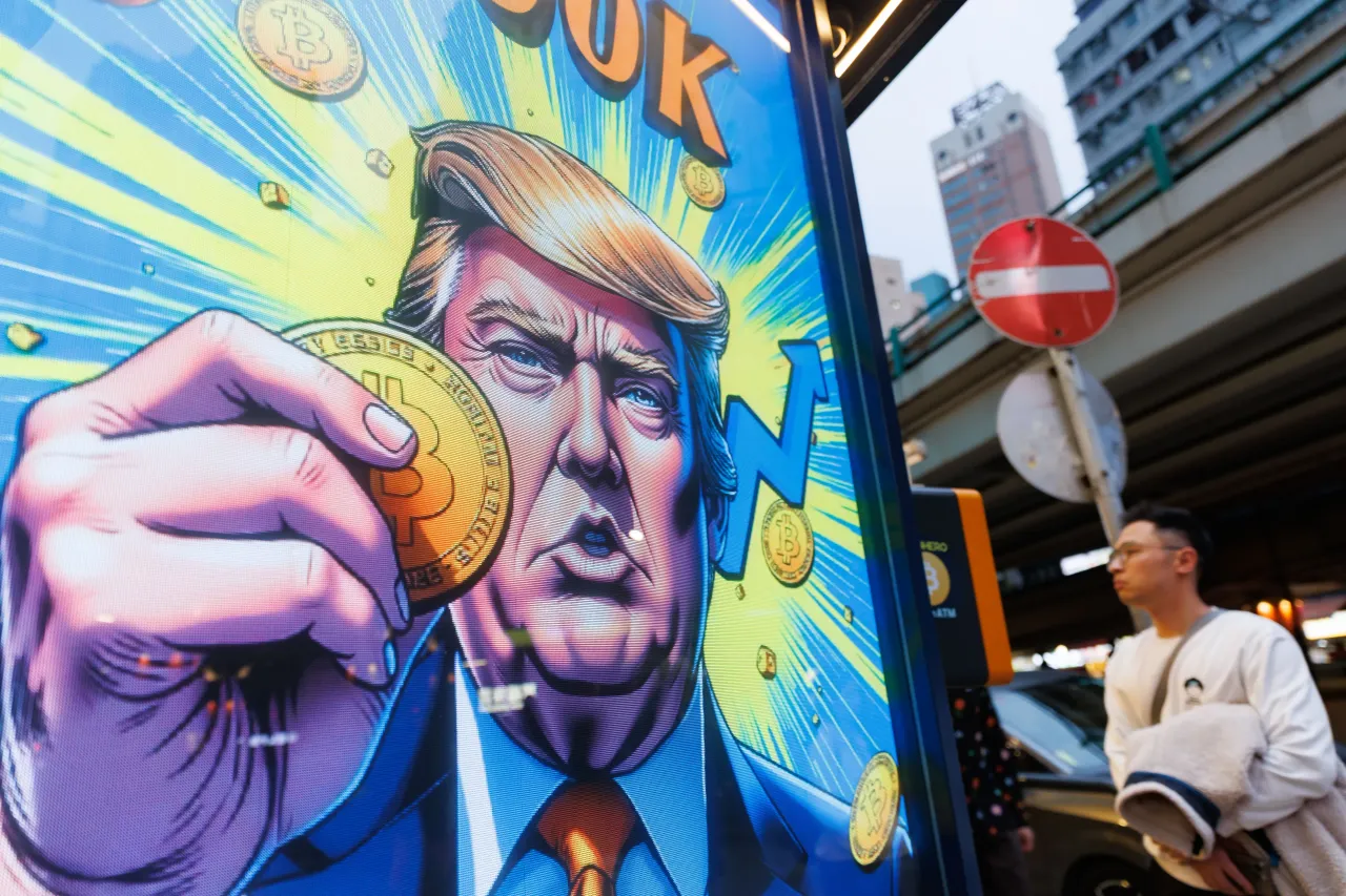 People walk past an advertisement feature Donald Trump with Bitcoin in Hong Kong. (Photo by May James/SOPA Images/LightRocket via Getty Images)