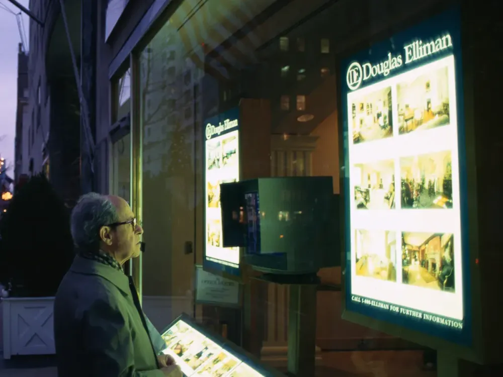 Man Reading Douglas Elliman Window Sign (Photo by mark peterson/Corbis via Getty Images)
