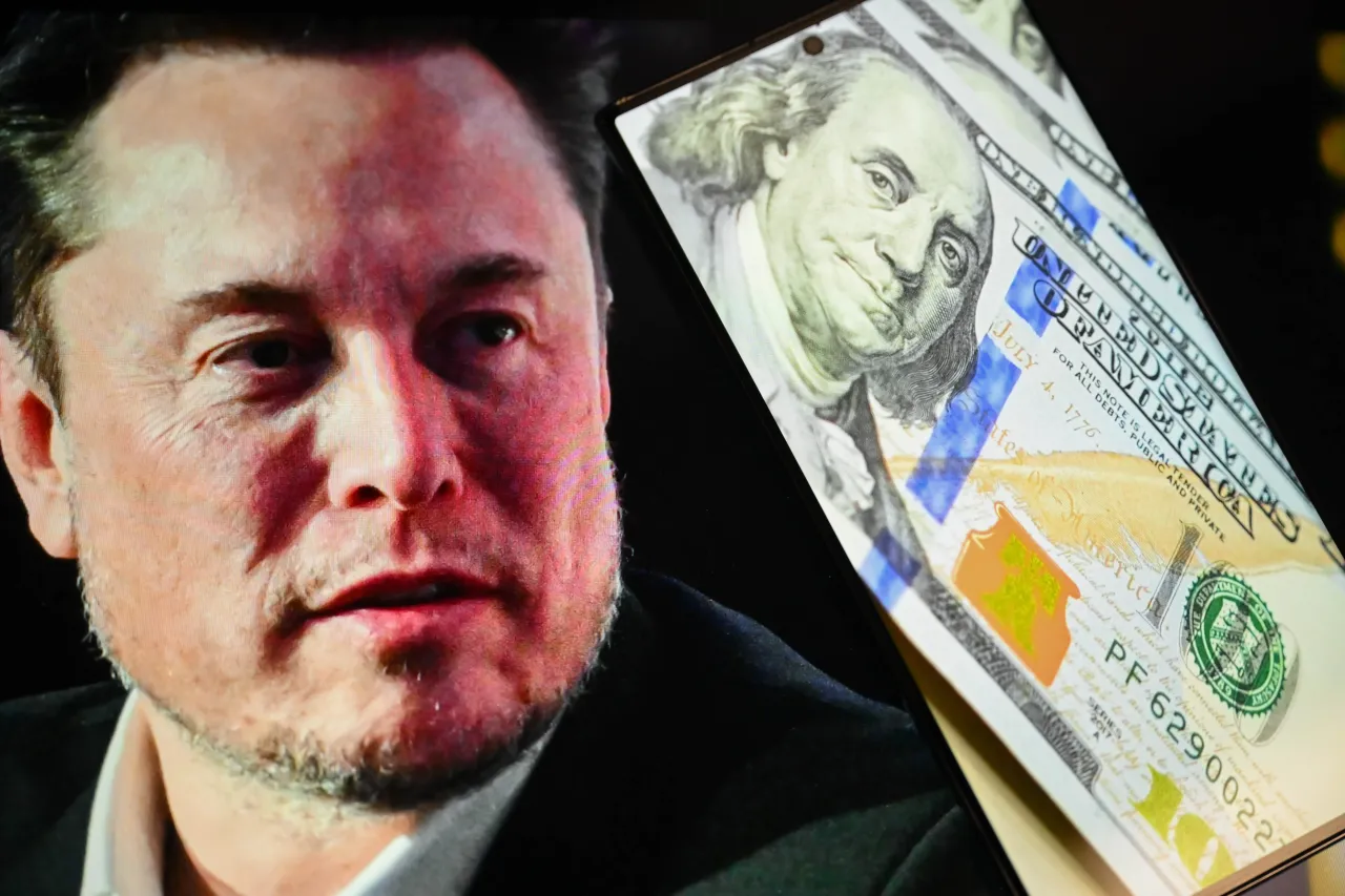 In this photo illustration, a portrait of Elon Musk is displayed on a computer screen behind a mobile phone screen on October 07, 2025. (Photo by Harun Ozalp/Anadolu via Getty Images)